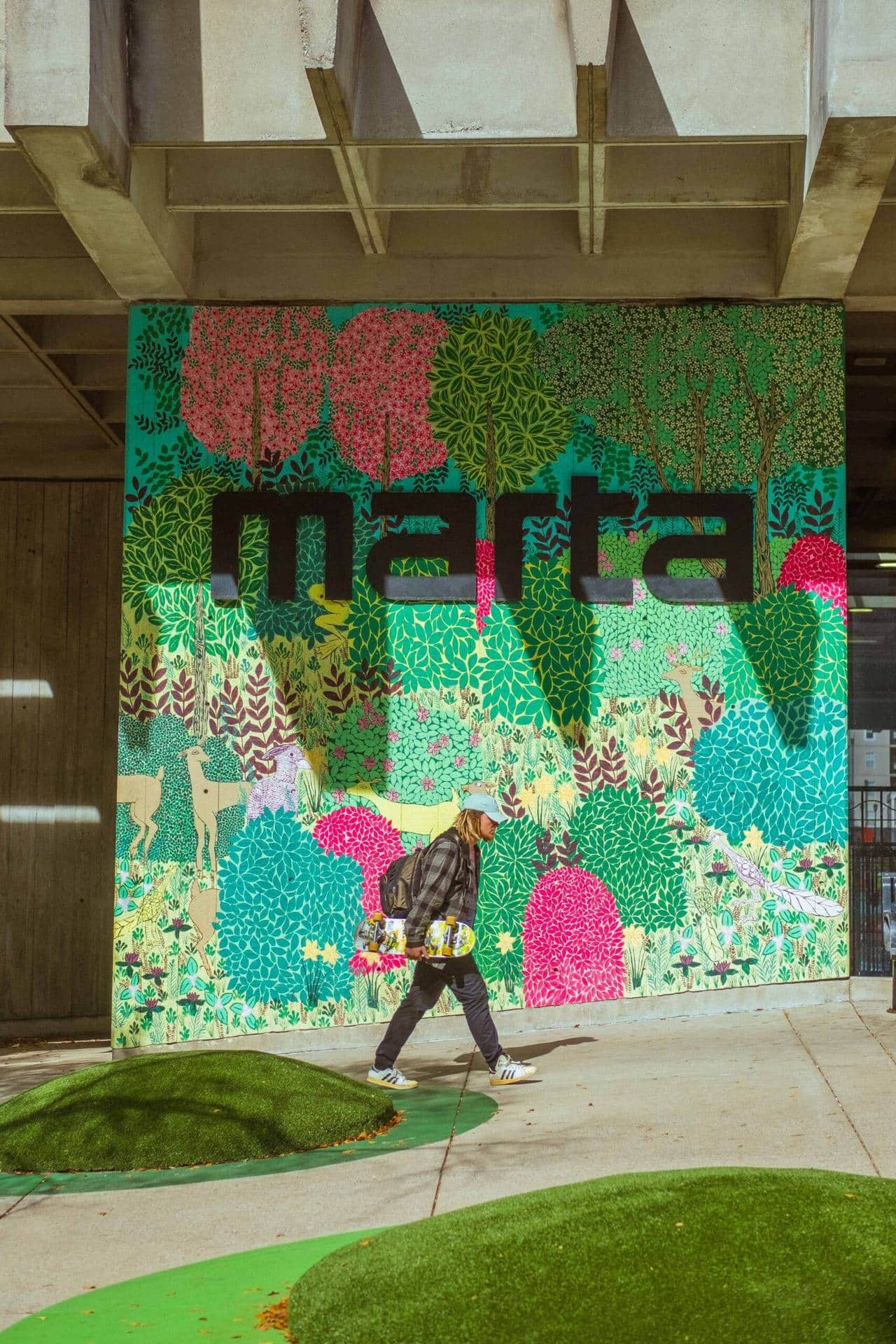 Person walking past a colorful Marta mural
